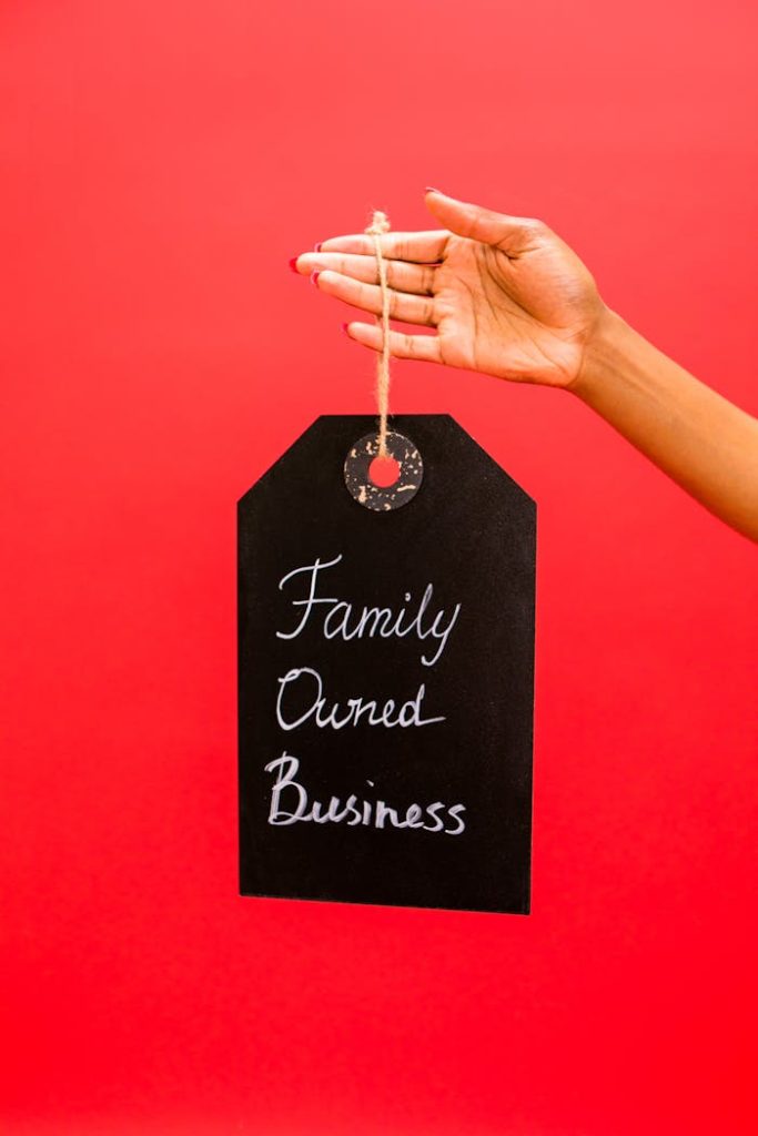 Hand holding a chalkboard sign reading Family Owned Business against a red backdrop.